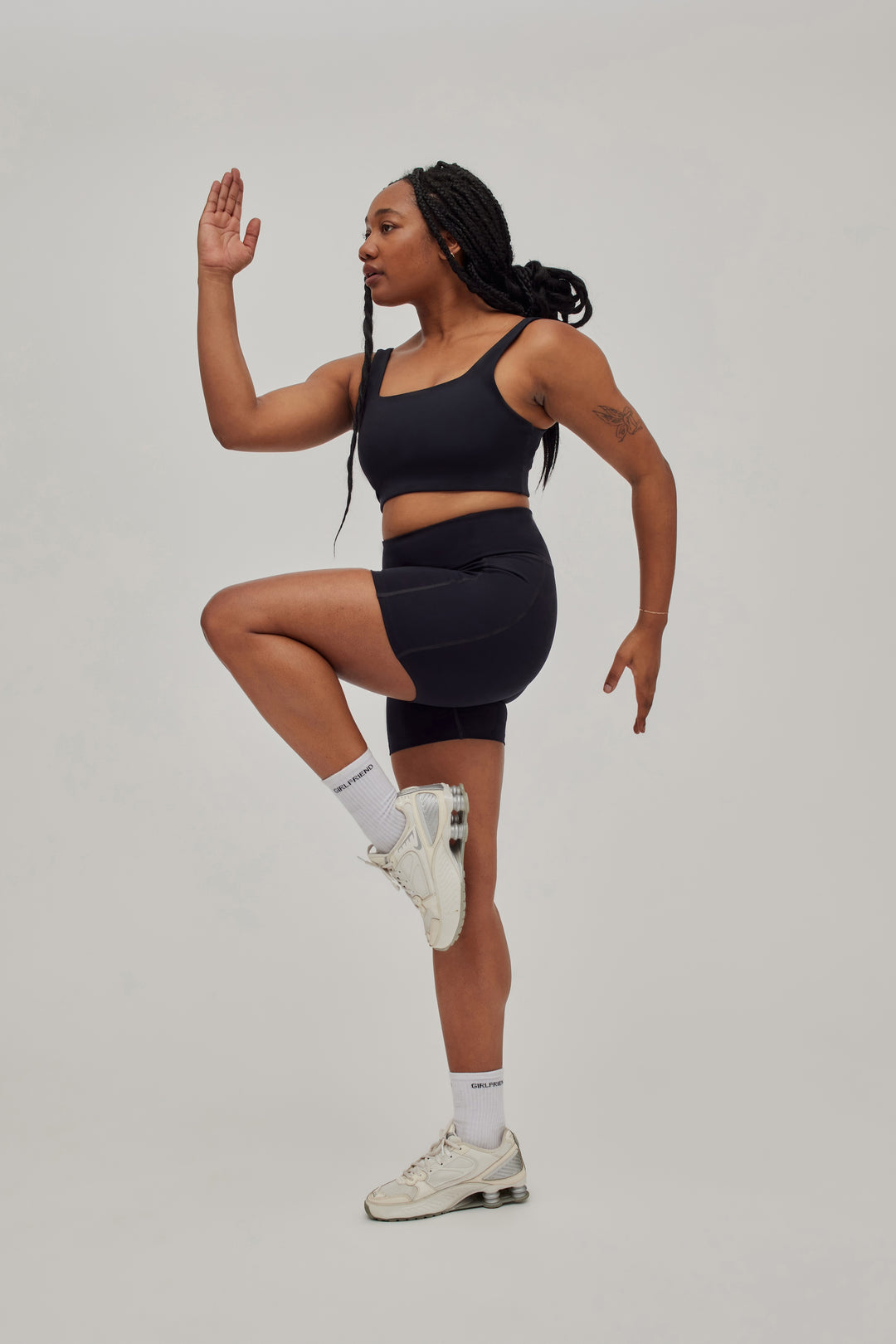 Model in running pose wearing Girlfriend Collective high rise running shorts in black