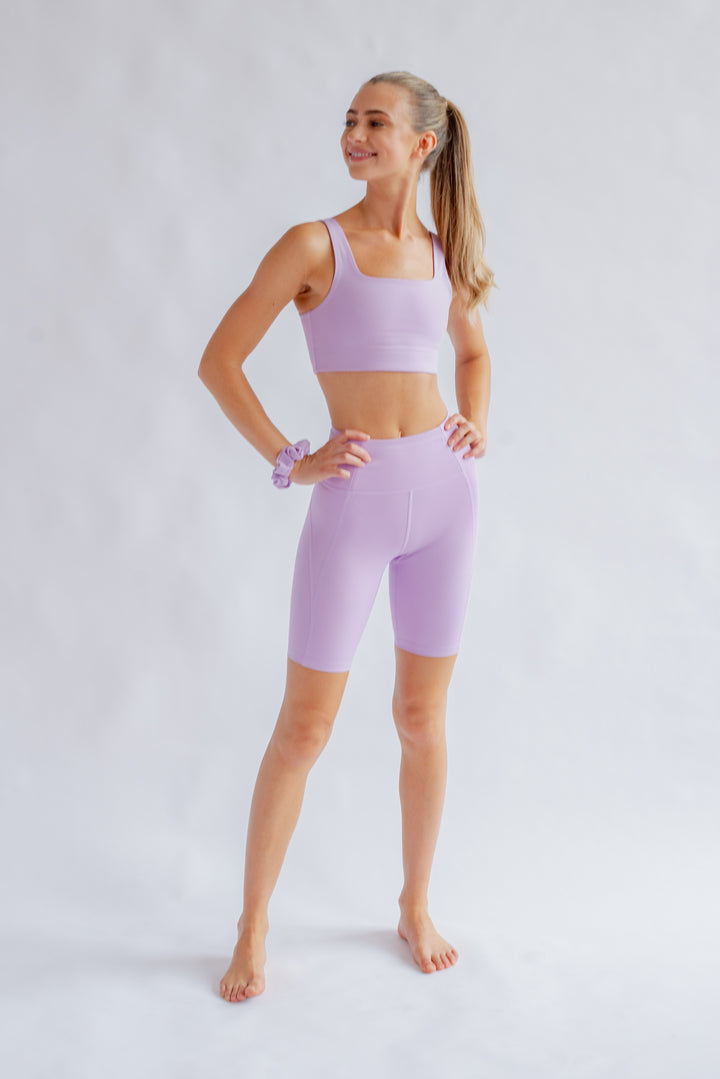 Angled front view of Girlfriend Collective pastel activewear shorts in Lilac